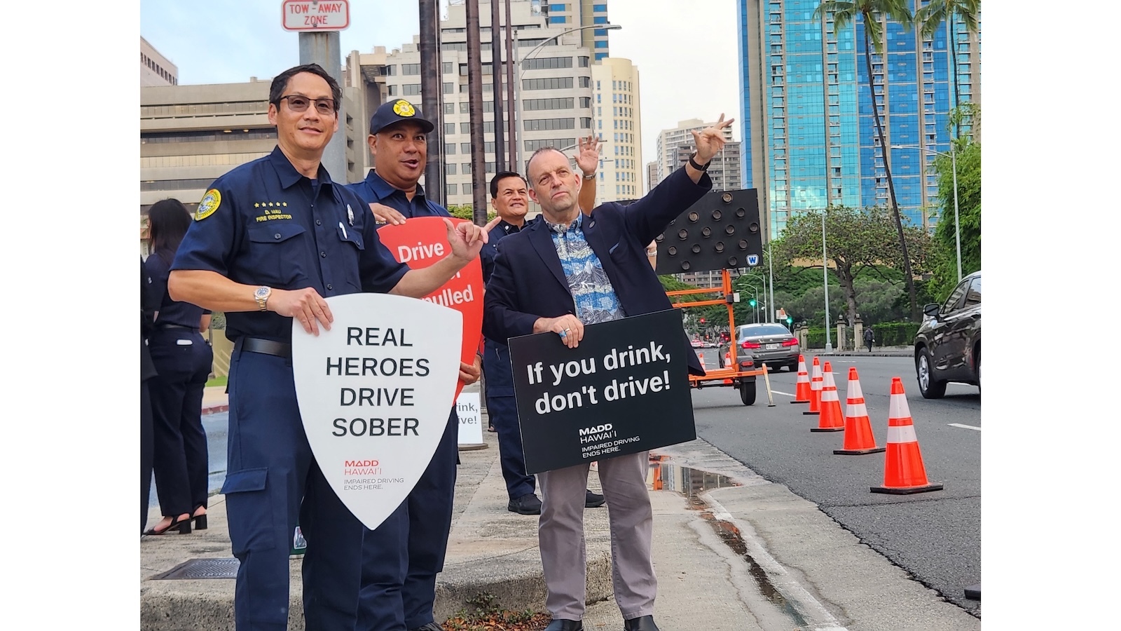 Gov. Josh Green waves signs promoting sober driving in front of the State Capitol Thursday.