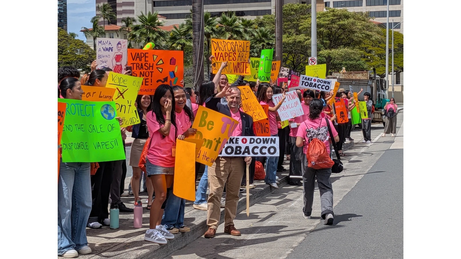 Gov. Josh Green waves signs with keiki outside the State Capitol.
