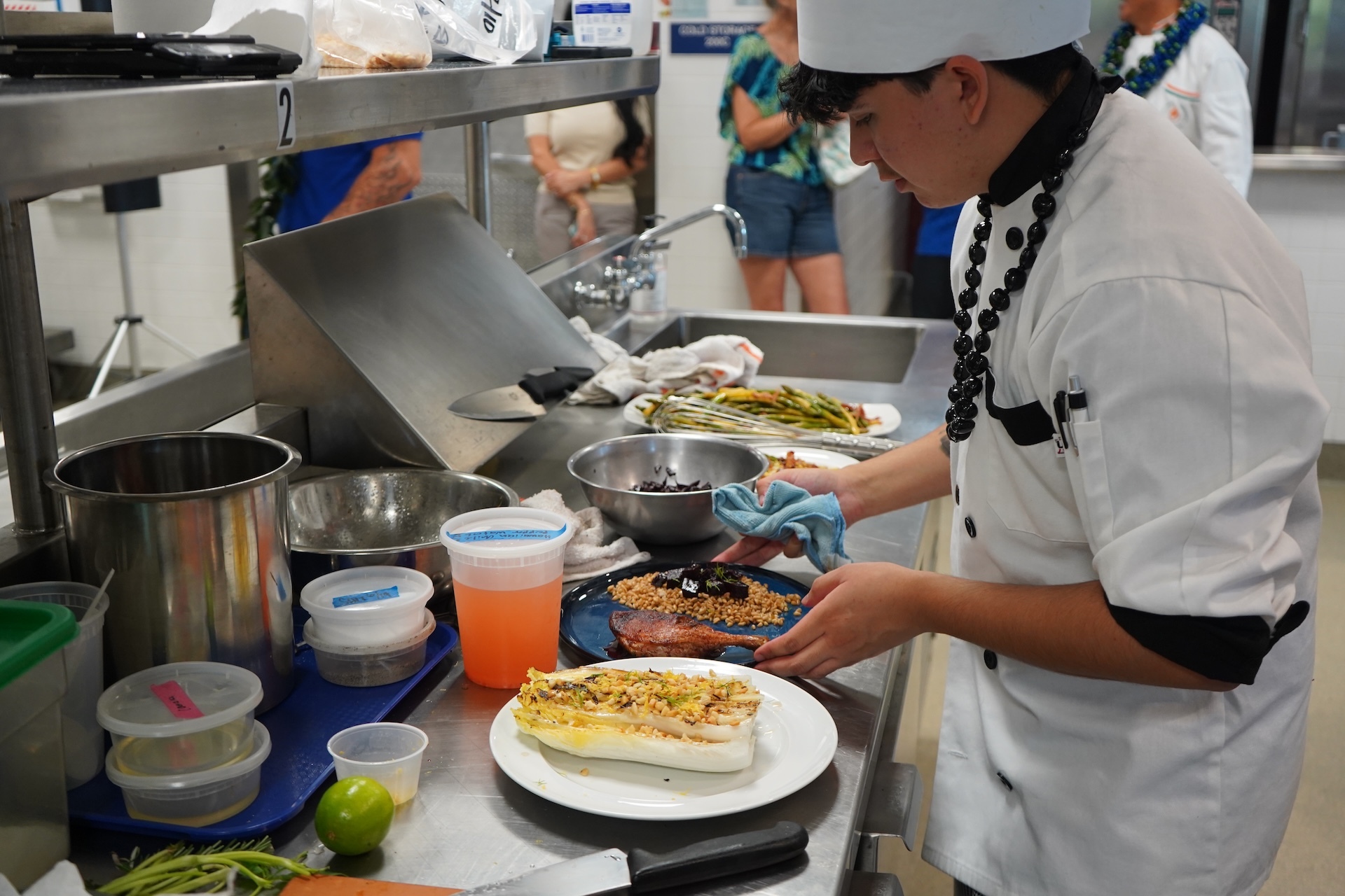 Student chef Kris Corrales plates his final dish: duck thigh with a beetroot and red wine sauce, with drippings from the duck, veggie and starch side. Photo by Kelsey Kukaua Medeiros