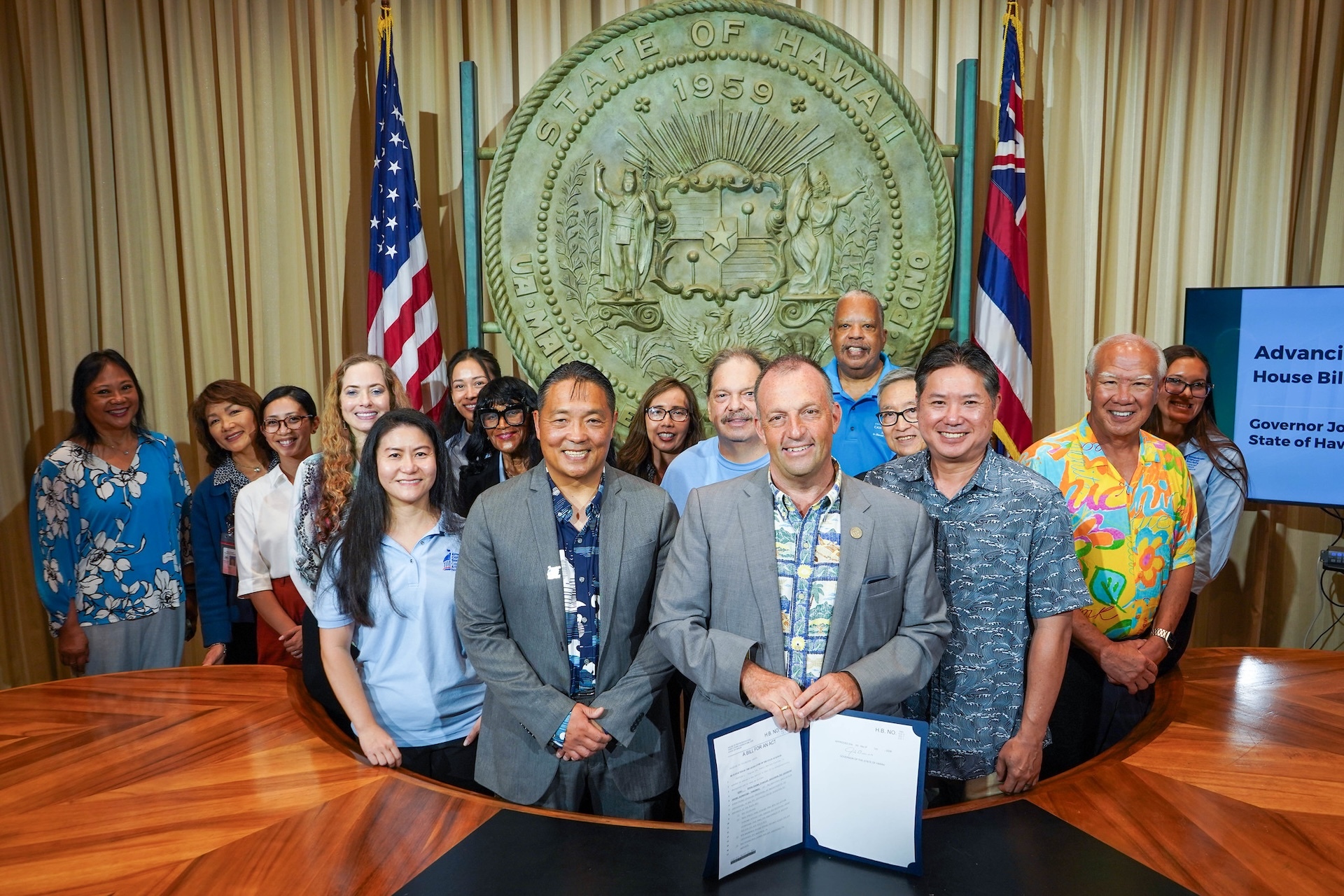 Gov. Josh Green pictured holding a signed HB 1969, which effective July 1, allocates state funding to increase access to colorectal cancer screenings and treatments statewide, along with lawmakers, doctors and members of the American Cancer Society Cancer Action Network Hawaiʻi team on Thursday, July 9, 2026.