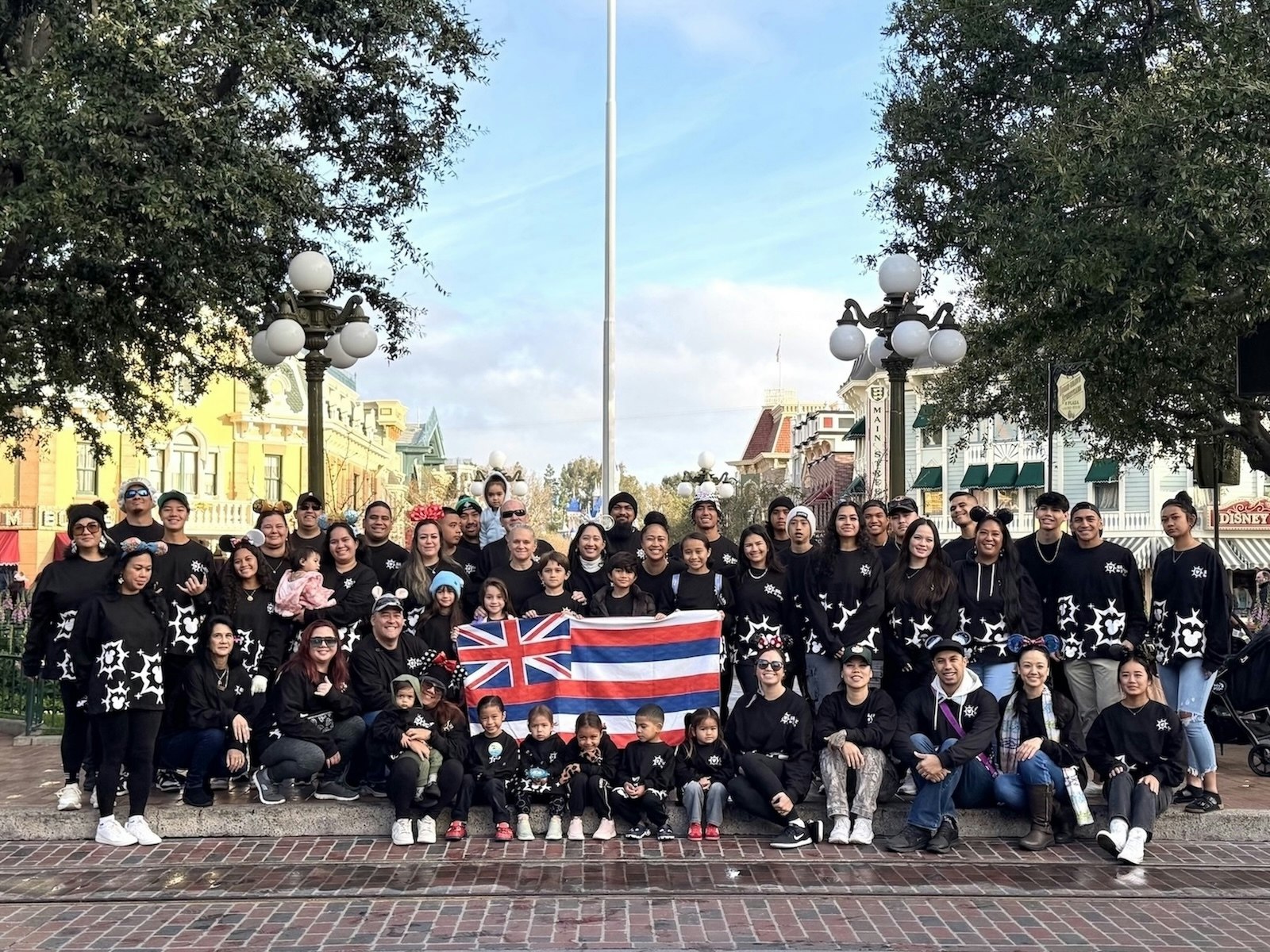 Group picture at Disneyland holding up Hawaiian flag.