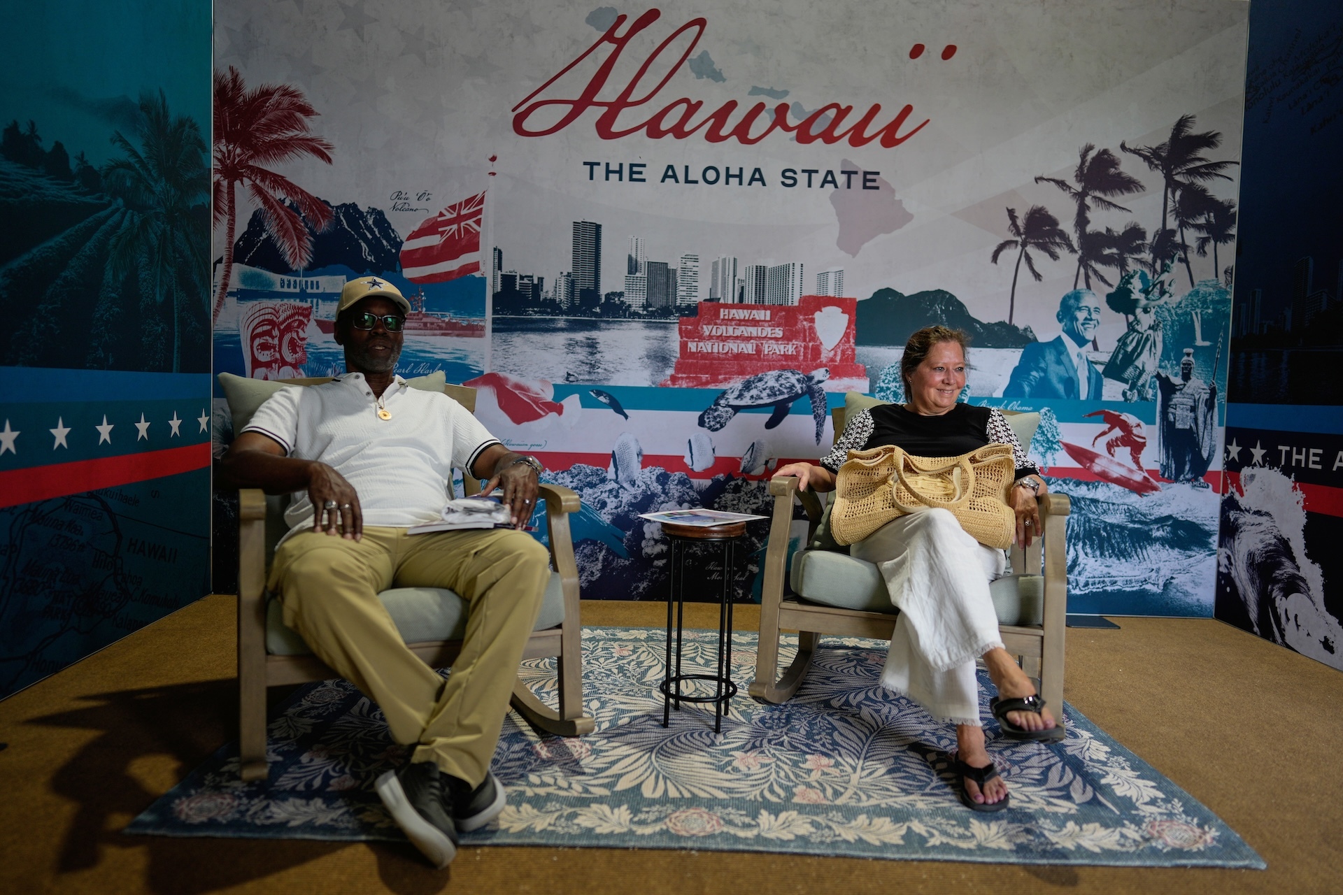 From left, Alonzo Lewis Jr. and Kelly Domizio sit in cushy chairs in Hawaiʻi's exhibit at the Great American State Fair on Friday, June 26, 2026, in Washington D.C. Photo digitally purchased from Associate Press Newsroom.