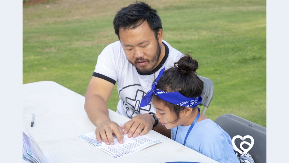 An adult male volunteer talks about the Bible with a female camper