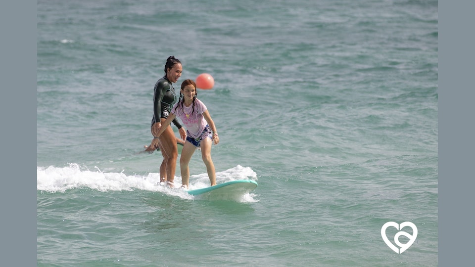 A surf teacher helps a camper surf at Camp Agape.