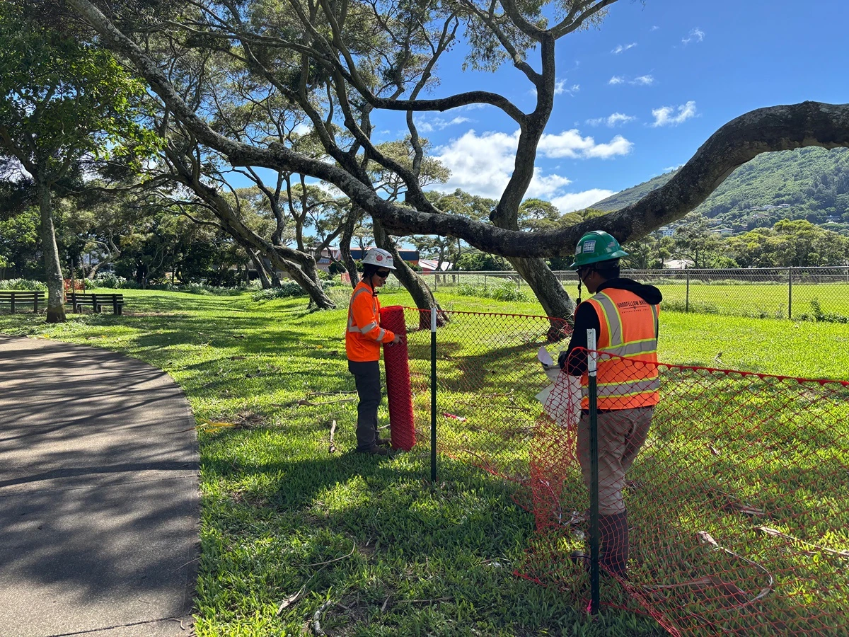 Two construction workers set up orange safety barrier fencing at Manoa valley District Park on Monday, Aug. 3, 2026. Flood mitigation activities started Monday.