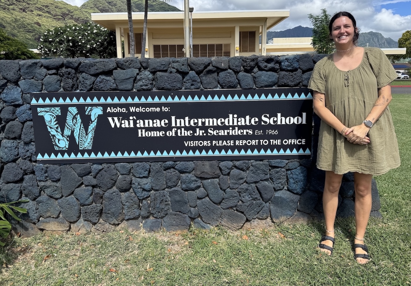 Kileigh Sanchez poses for a photo beside the Waiʻanae Intermediate School sign, where she teaches seventh and eighth grade art. Sanchez earned Hawaiʻiʻ's 2027 Complex Area and Charter School Teachers of the Year award in recognition for her work reestablishing the school's art program.
