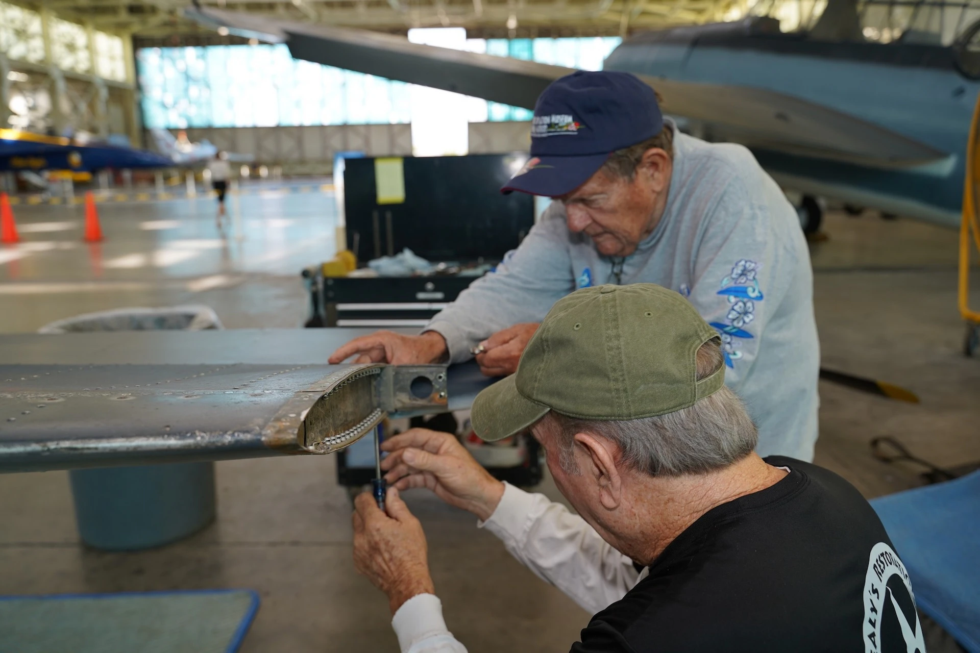 Montgomery (wearing blue cap) and Mark Erwin disassemble a stabilizer on the tail section of an SBD-5 Dauntless, a World War II-era dive bomber. Credit: PHAM.