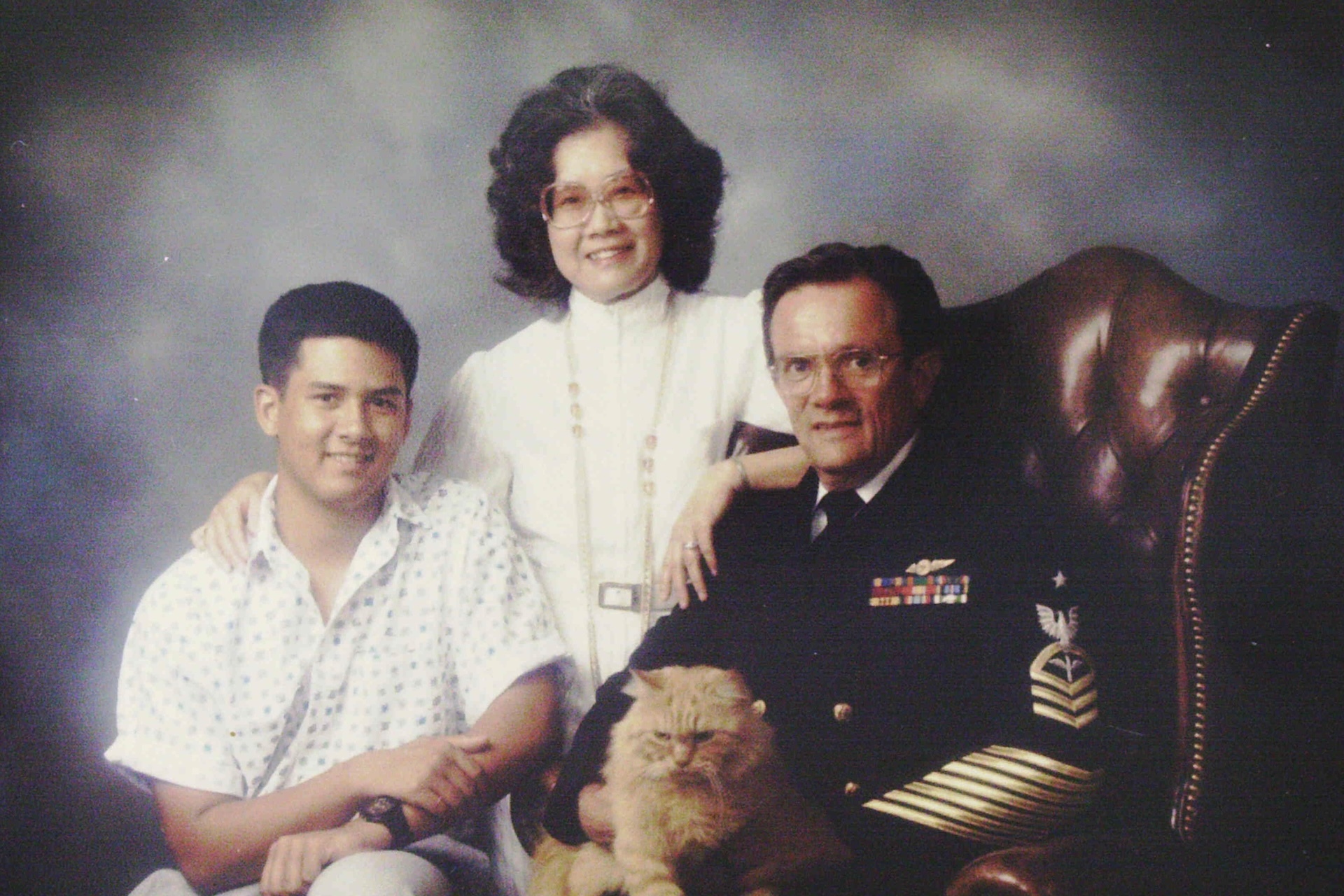 Portrait of the Montgomery family, circa 1988: Montgomery, dressed in his senior chief petty officer uniform; his wife, Teruko; their son, Richard, who was in high school at the time; and Tiger, the cat. Credit: Courtesy of Ron Montgomery.