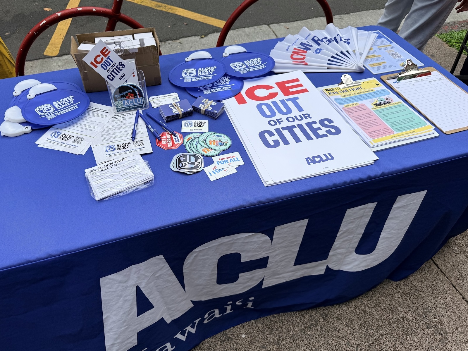 ACLU of Hawaiʻi table pictured along with some Aloha State Daily merchandise. Photo by Kelsey Kukaua Medeiros