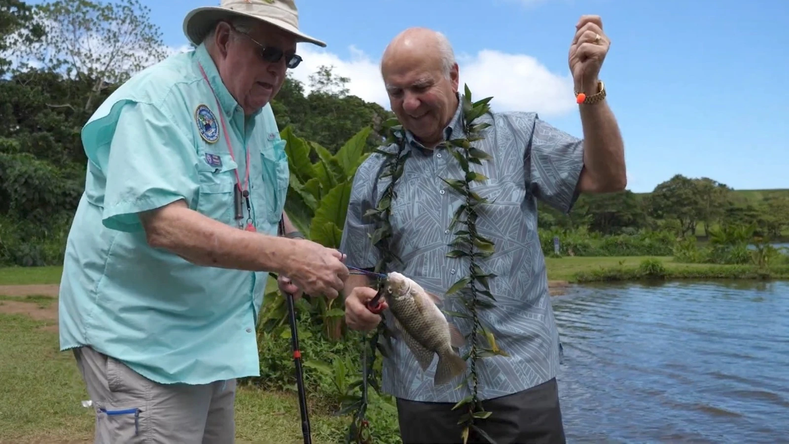 Honolulu Mayor Rick Blangiardi, right, and Stan Wright of Scouts U.S.A. unhook a tilapia at Ho‘omaluhia Botanical Garden’s Loko Waimaluhia.