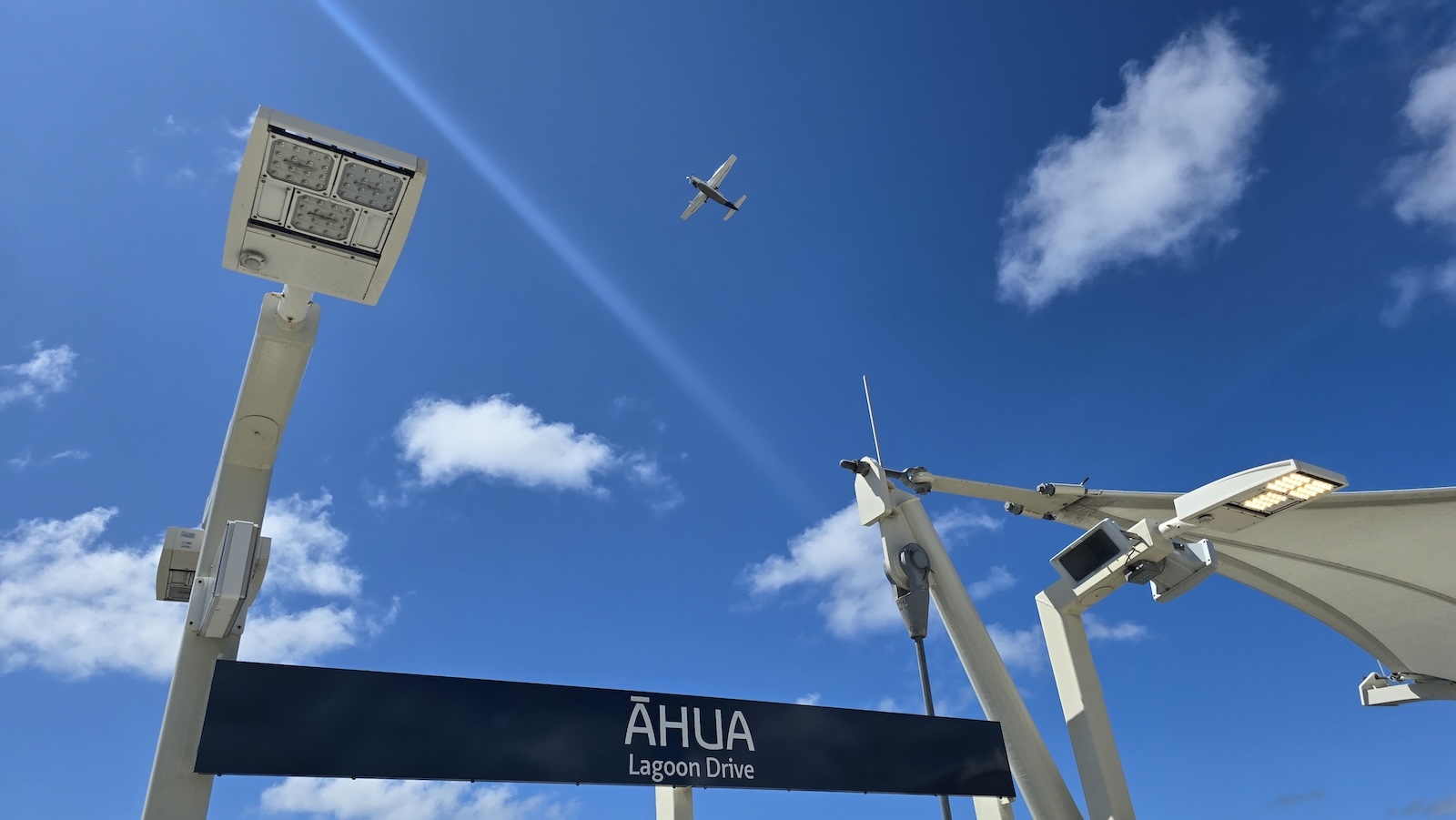 A plane flies over the Āhua, or Lagoon Drive, Skyline rail station.