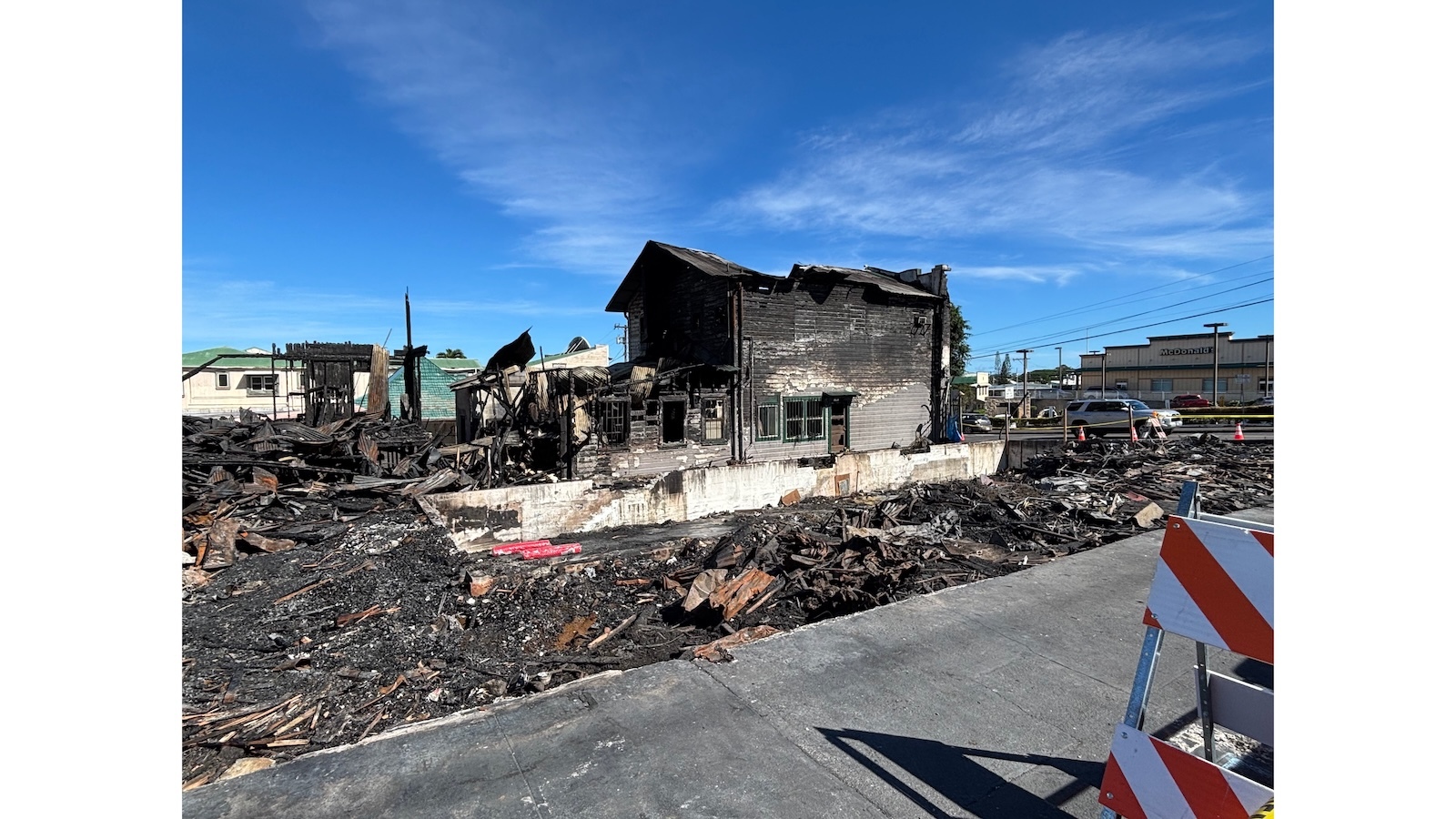 A fire-blackened corner of a building stands amid a field of wreckage