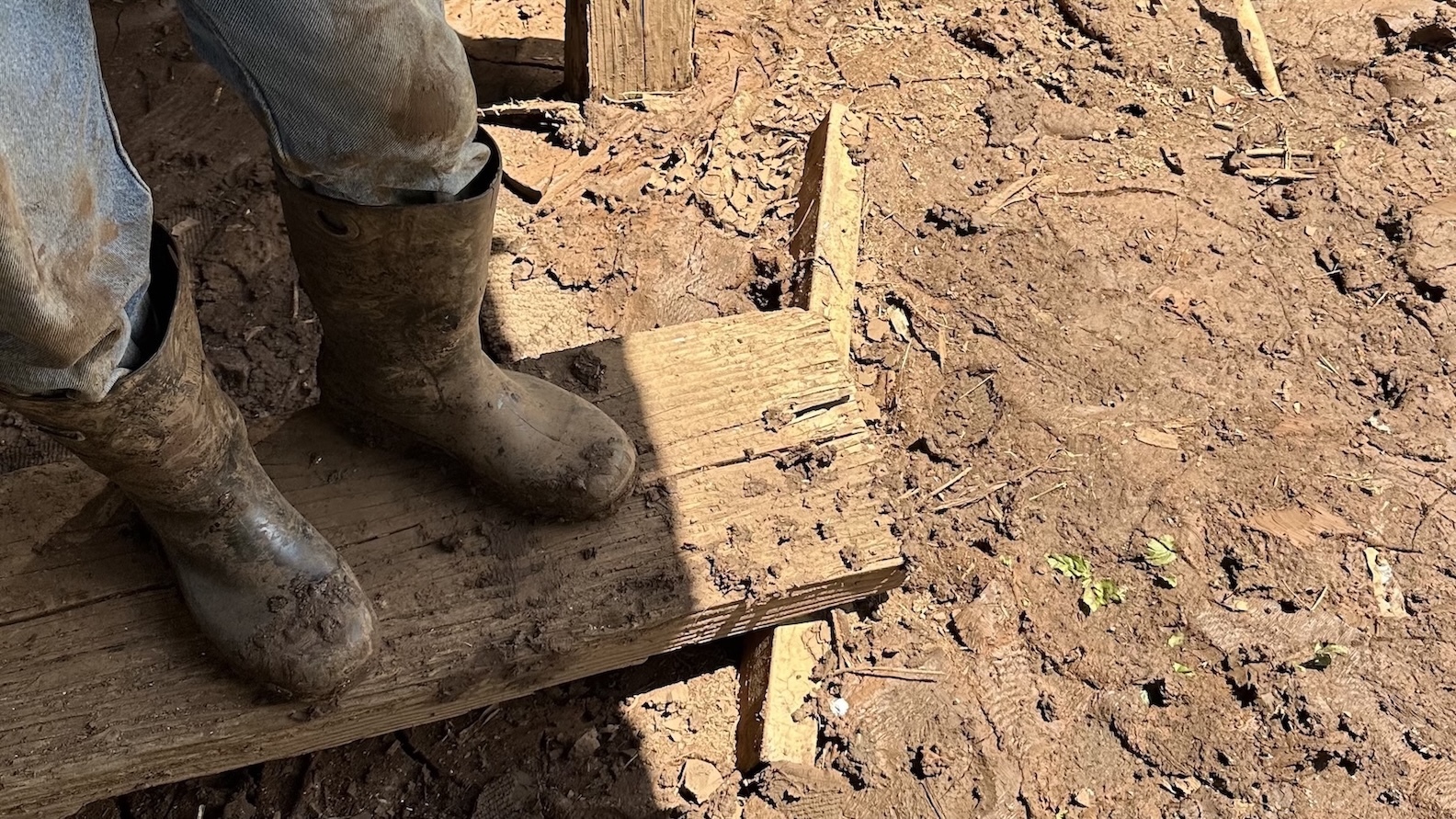 Thy Cavan wears boots at Otake Camp as he stands near his tractor, which was a total loss.