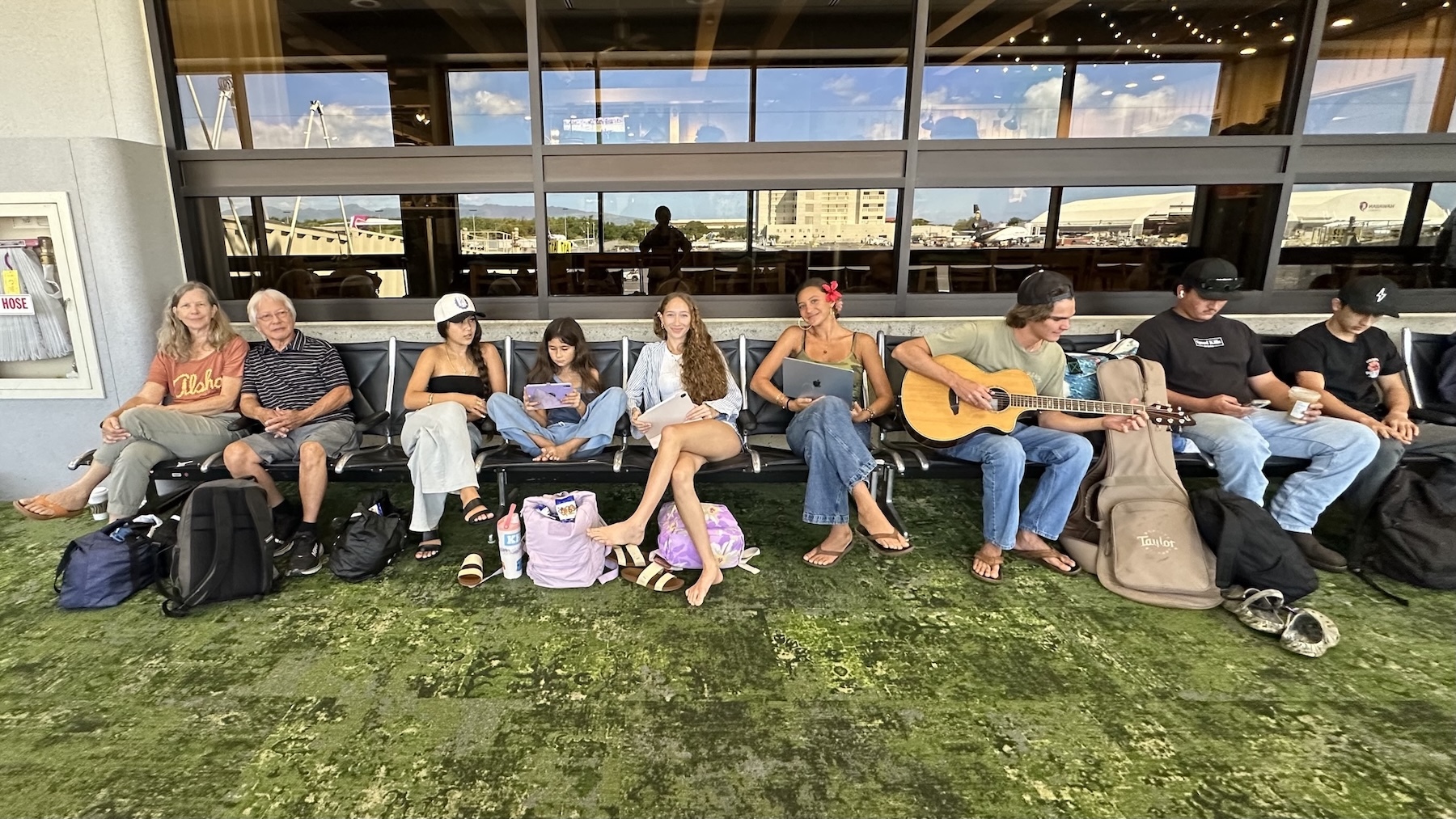 Festival founders Anne and Milton Lau, far left, wait for a plane with six grandkids and two girlfriends at the Daniel K. Inouye International Airport in Honolulu. From left to right: Anne Lau, Milton Lau, Olena Lau, Haukea Lau, Kala Lau, Pumehana Rochlen, Ryder Briley, Elijah Lau, and Micah Lau.