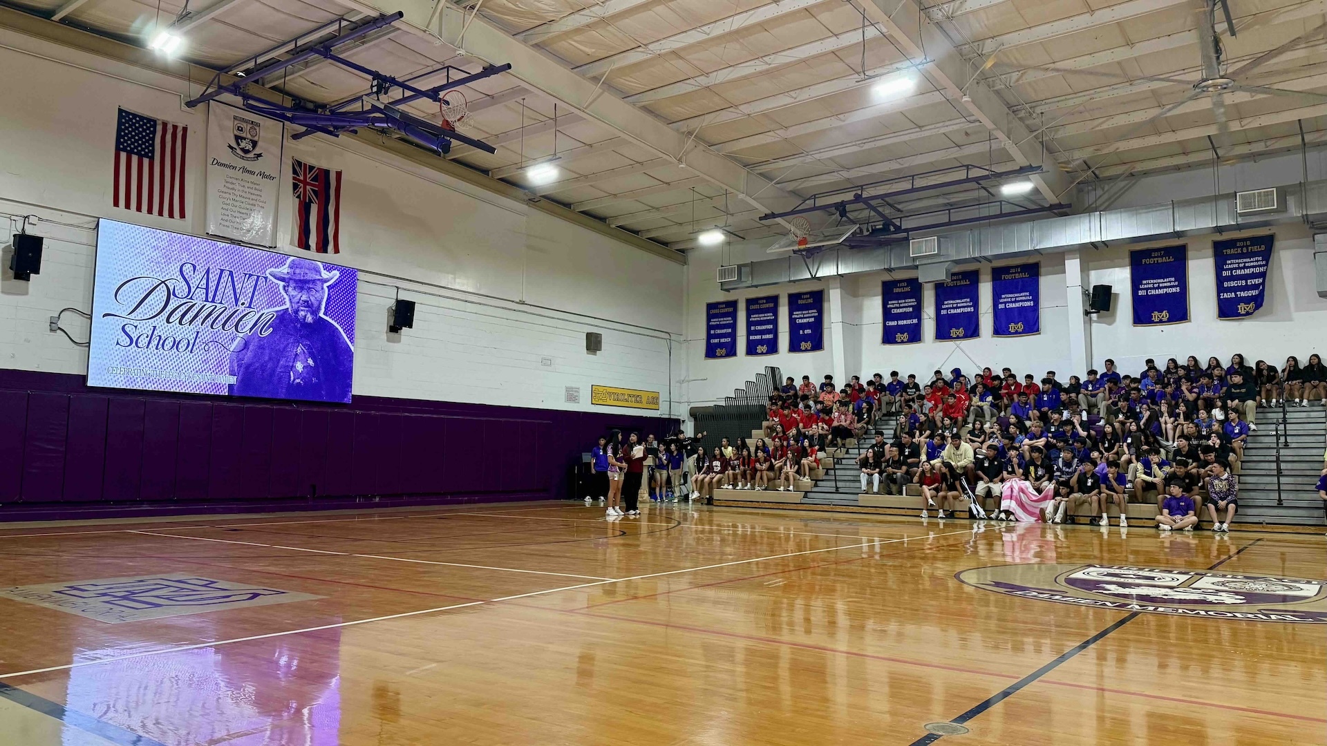 The homecoming assembly held Monday afternoon at the newly dubbed Saint Damien School was a surprise for students put on by the school’s student government. The gym erupted with cheers as 6th to 12th grade students participated in a trivia contest about Saint Damien, student versus teacher volleyball games and more. Photo by Kelsey Kukaua Medeiros